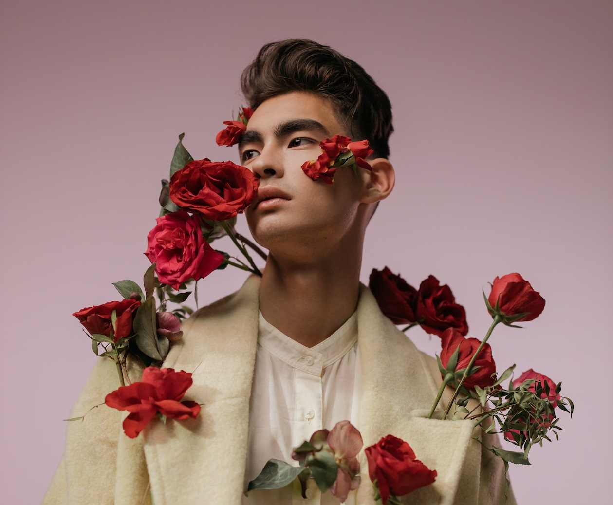 Man in beige long sleeves with red roses on him.