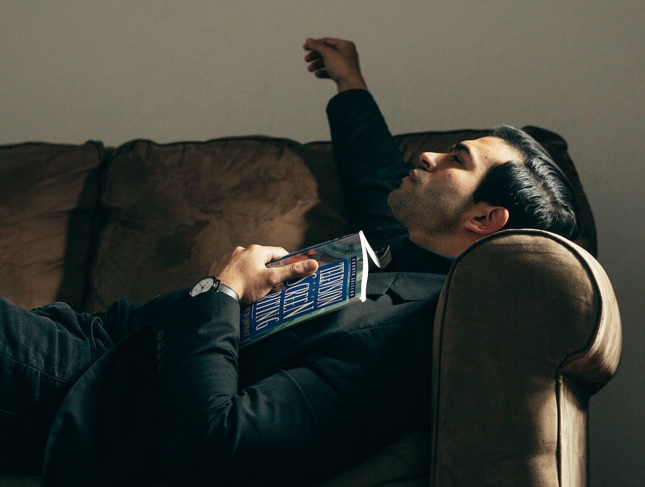 Man is laying on the bed,holding a book in his hand.