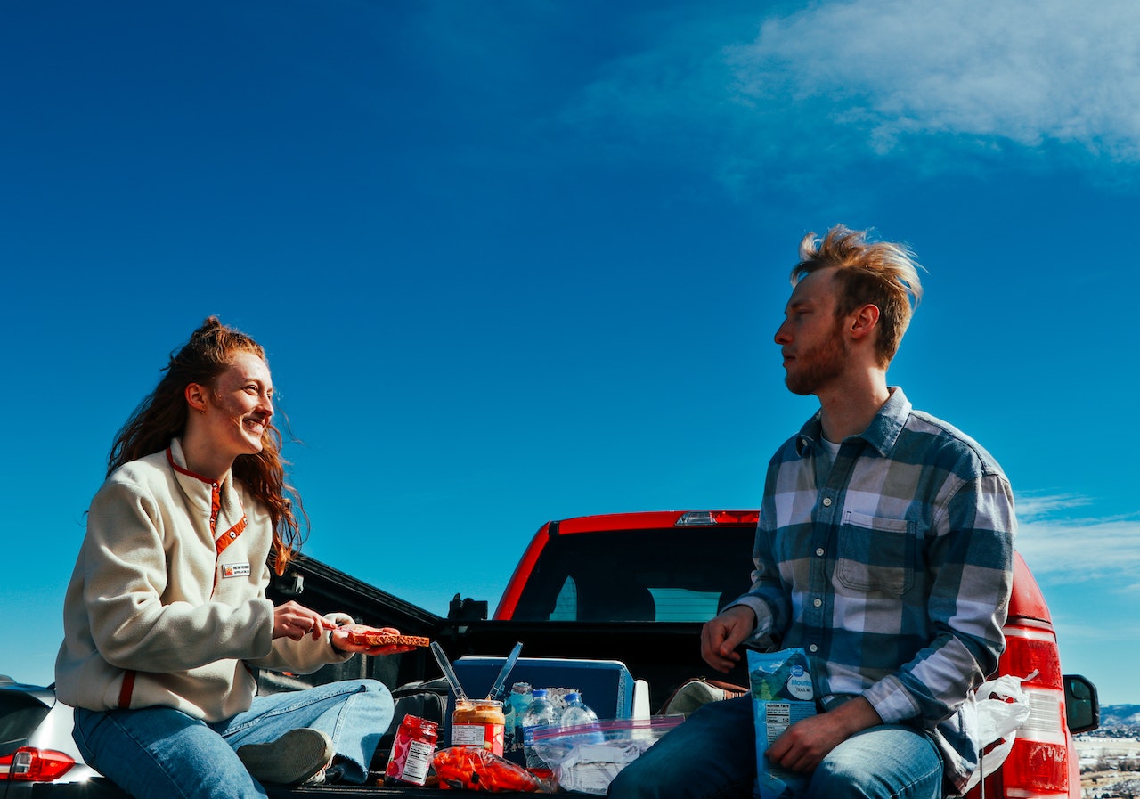 Man and woman sitting on the back of a pick up truck.