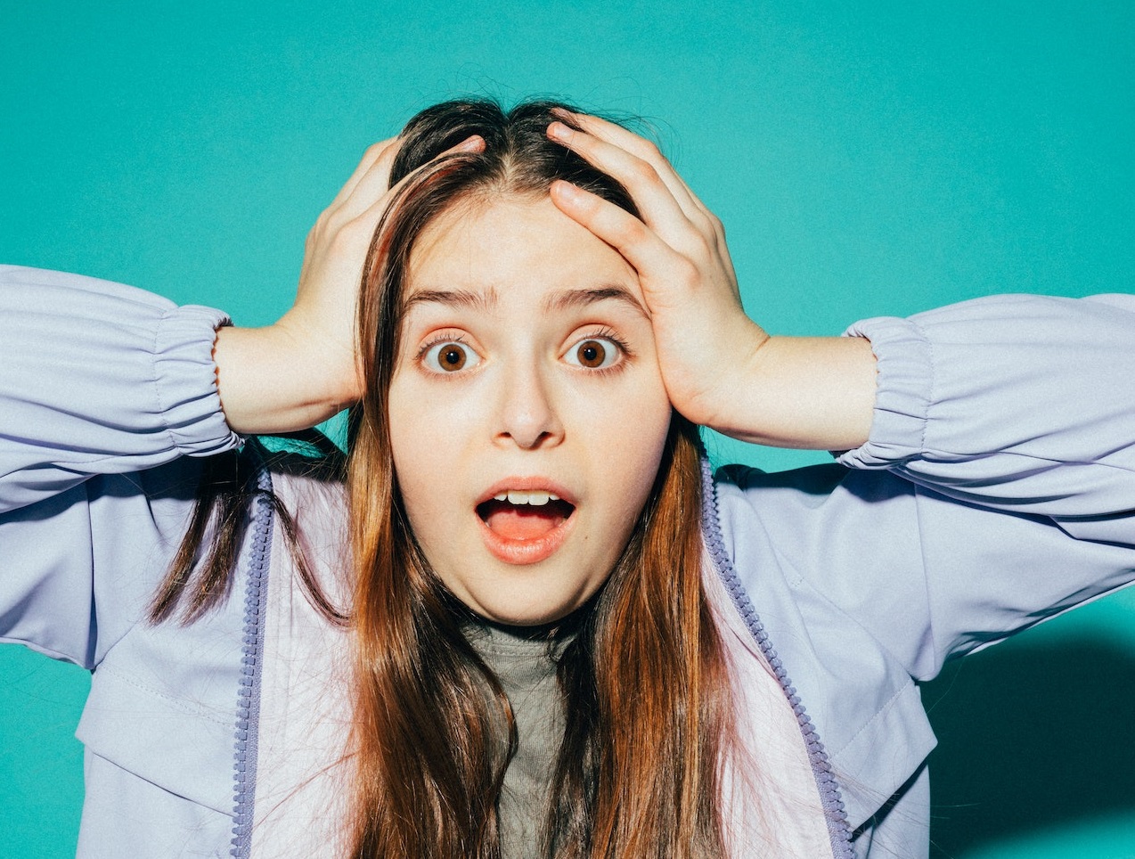 Young girl is holding her head and looking surprised.