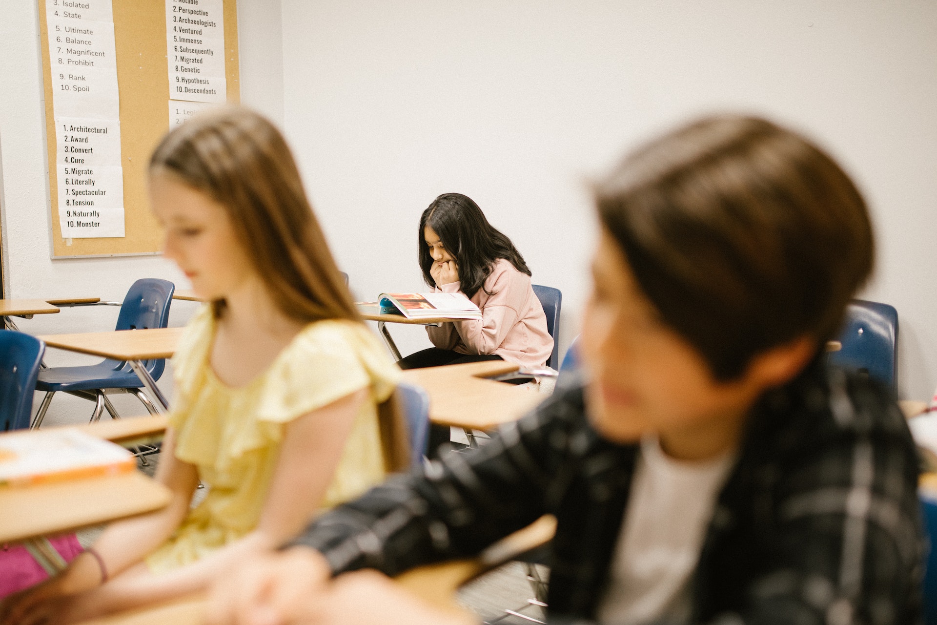 Children sitting at school room at desks reading books