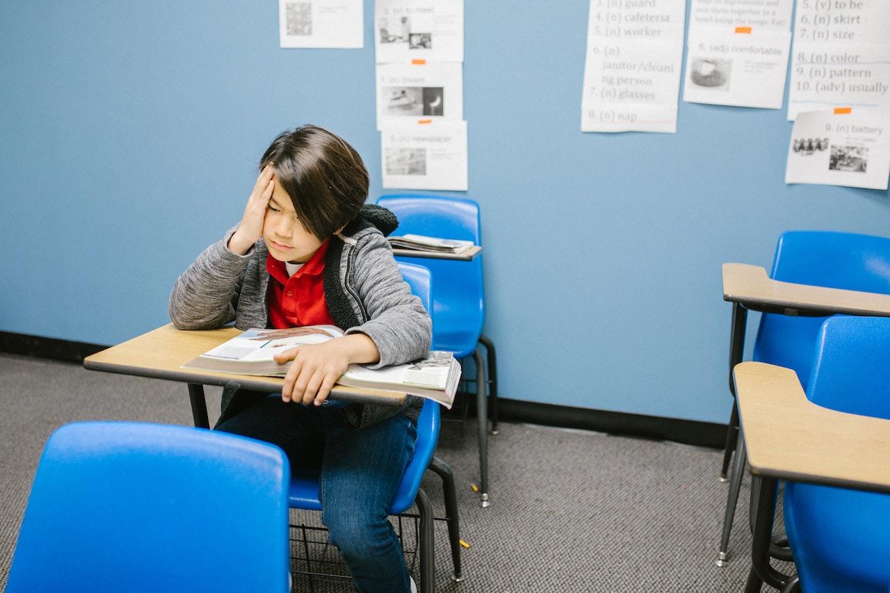 Sad boy sitting on his desk at classroom.
