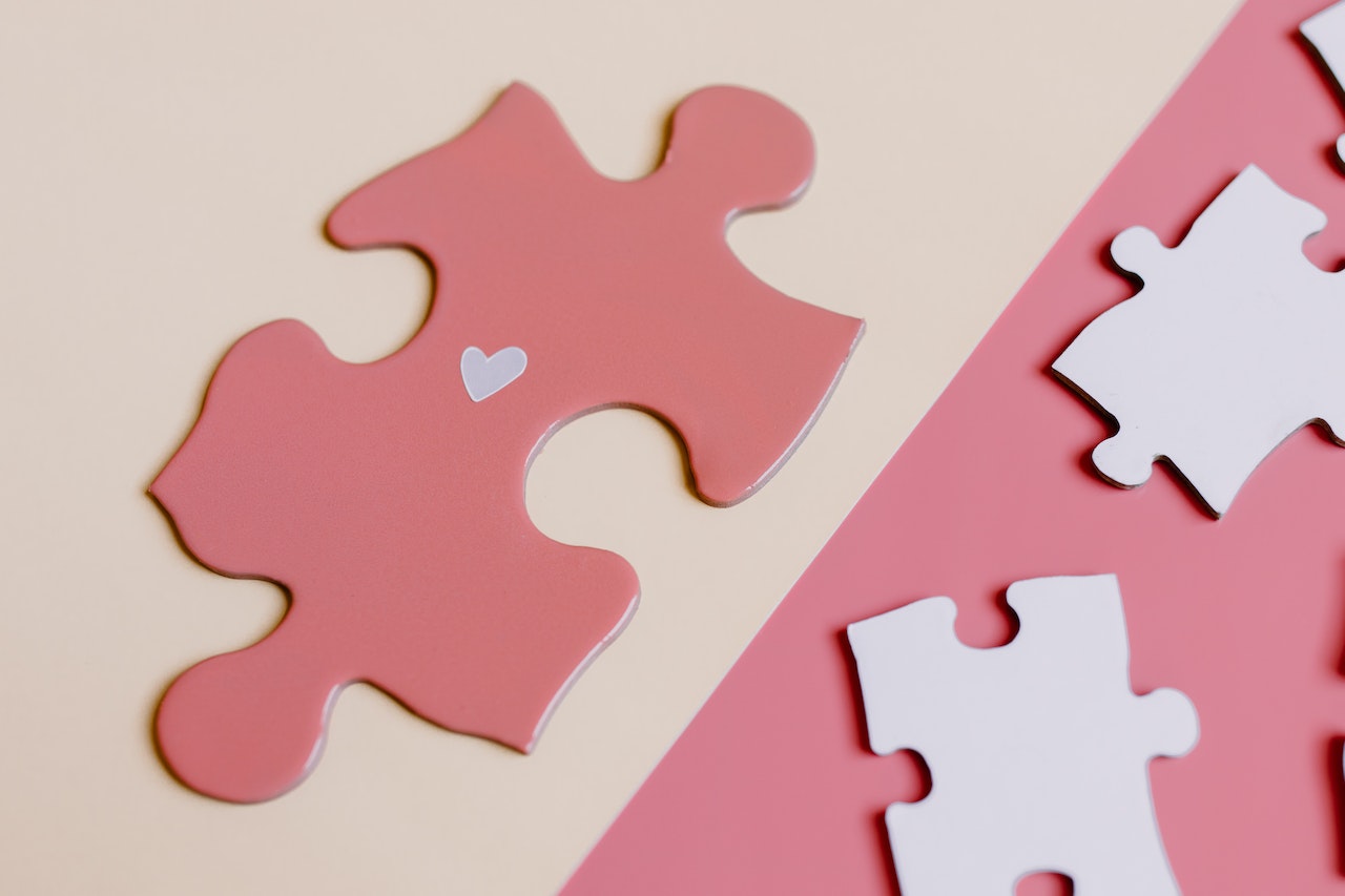 A pink puzzle piece with heart shape on the table.