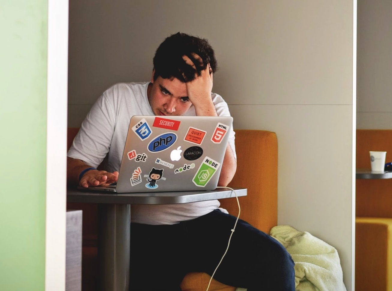 Sad man is working on laptop ,holding his head.