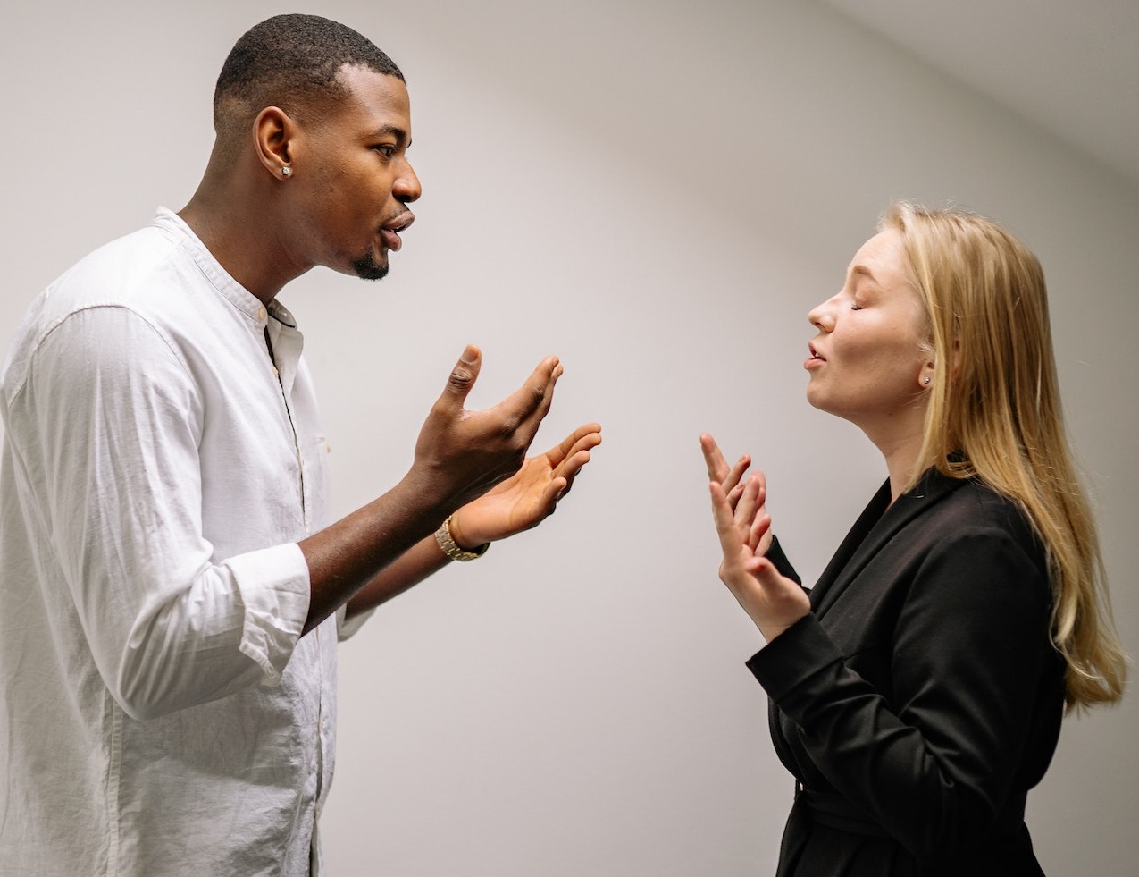Man wearing white shirt is arguing with woman with blonde hair and black jacket.