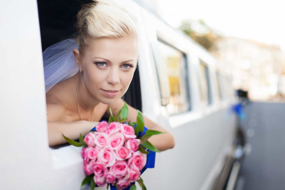 Bride looking trough limousine window arriving at wedding venue