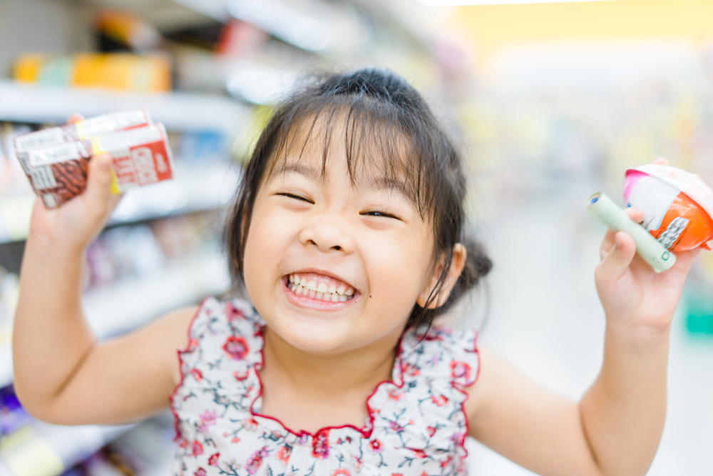 Happy Little asian girl holding Kinder Surprise Chocolate Eggs and smile