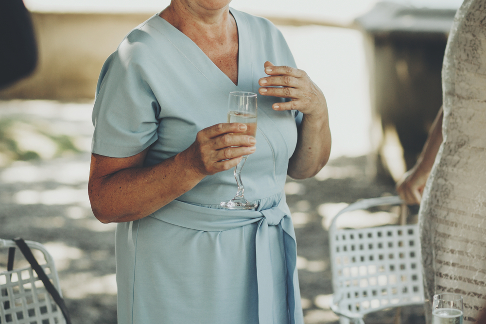 Stylish old woman holding glass of champagne at a wedding