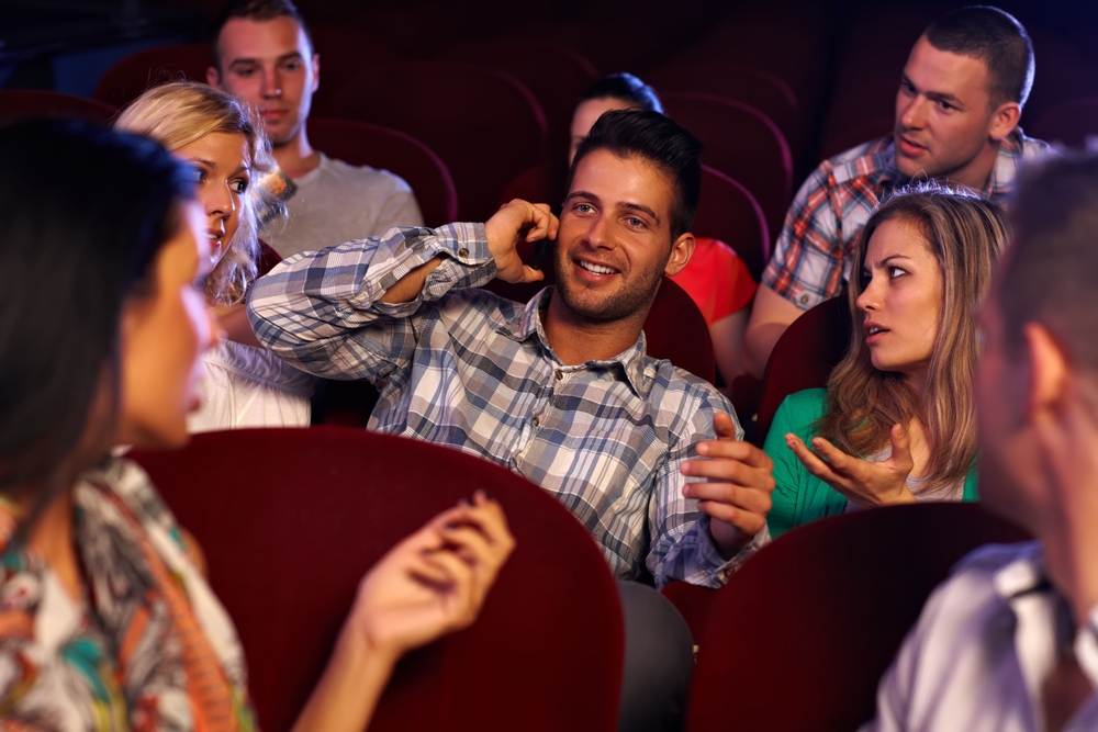 Angry people at a man speaking on the phone at the movie theatre