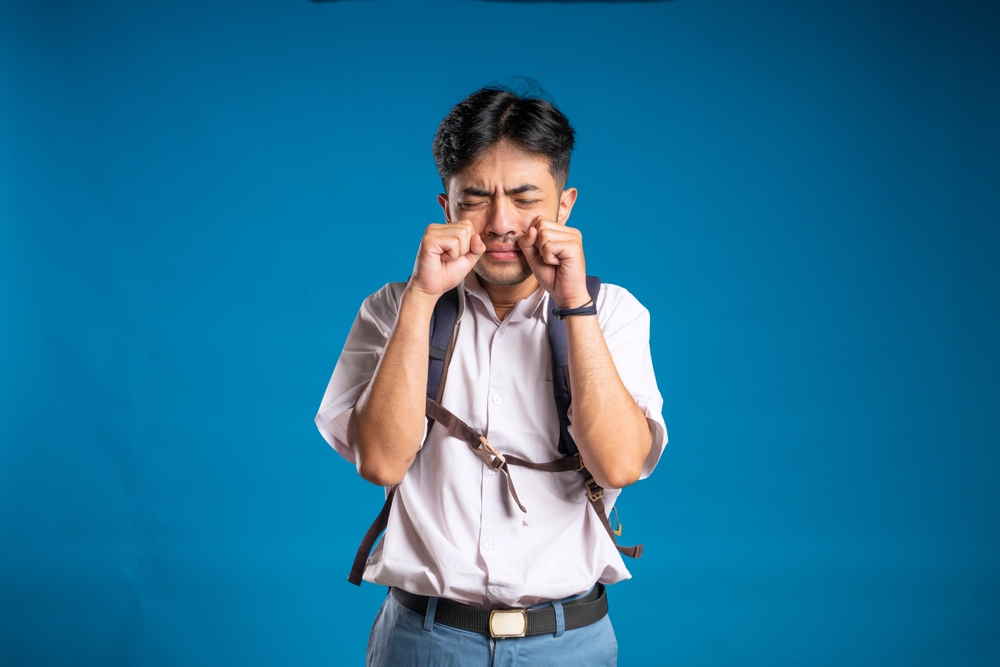 Kid crying because he is being bullied at school wearing a shirt and backpack