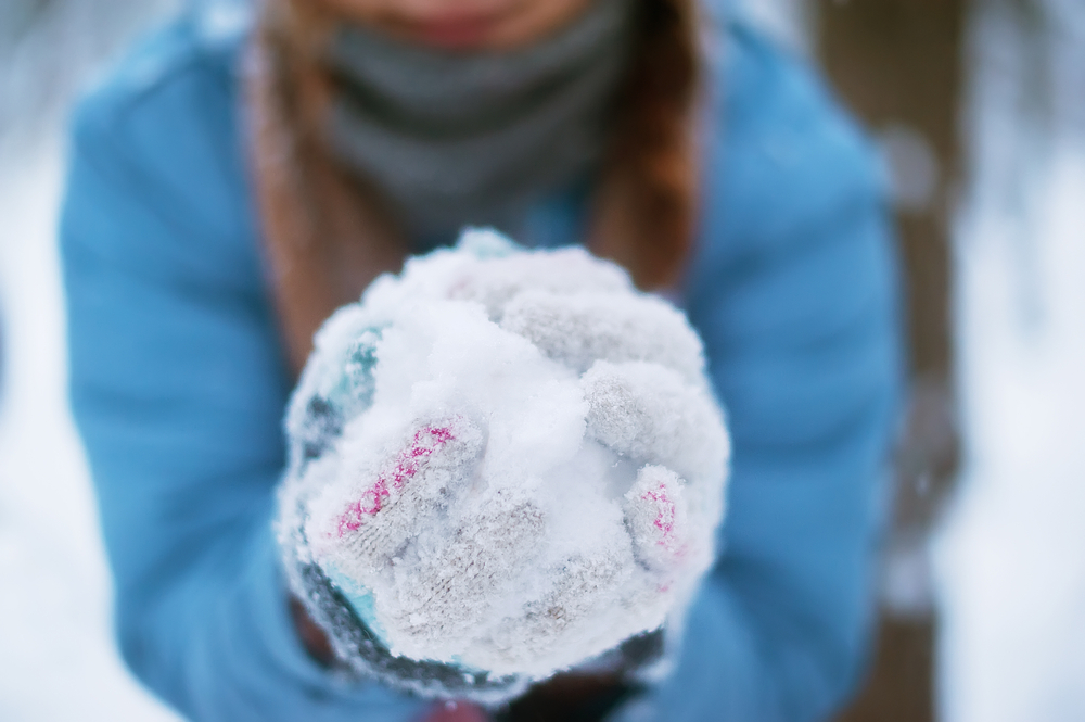 Woman holding  snowball in hands ready to throw it