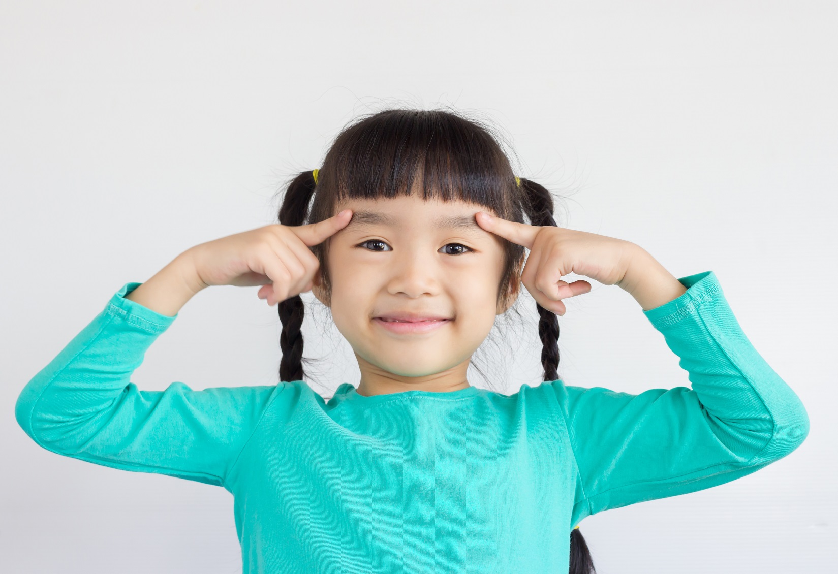 Asian child pointing at her eyebrows.