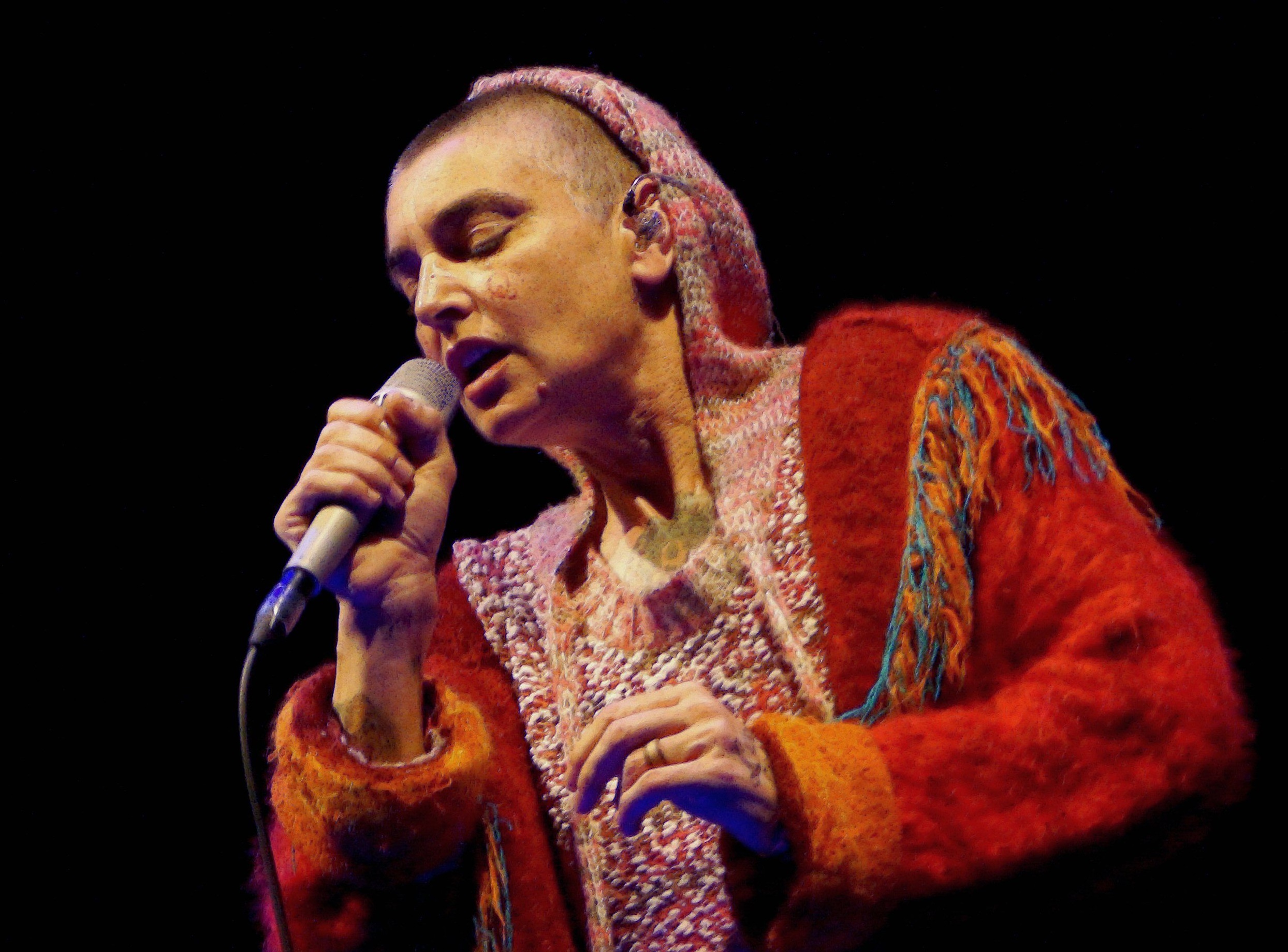 Sinéad O'connor wearing red clothes performing live on stage - 2013