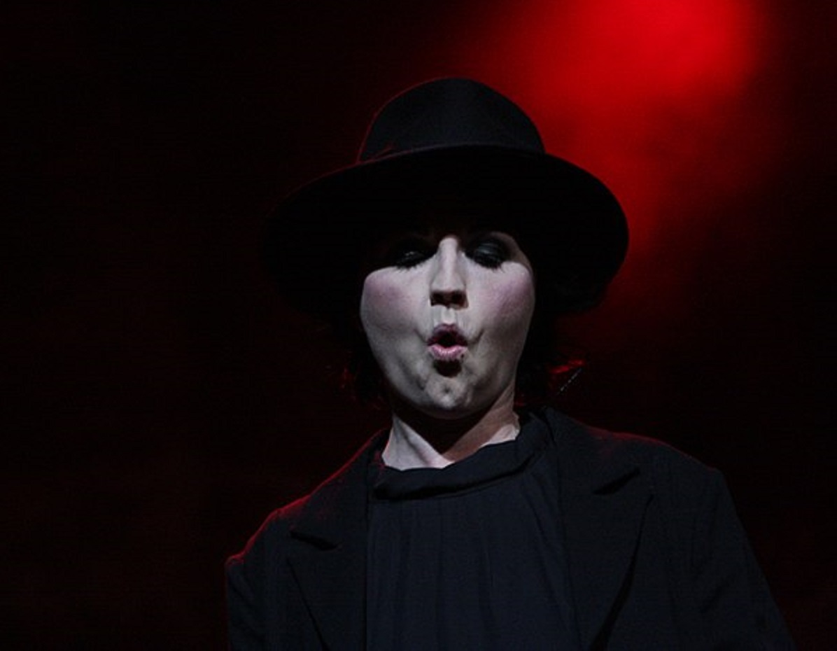 Dolores O'Riordan is performing on stage on black and red background - 2012