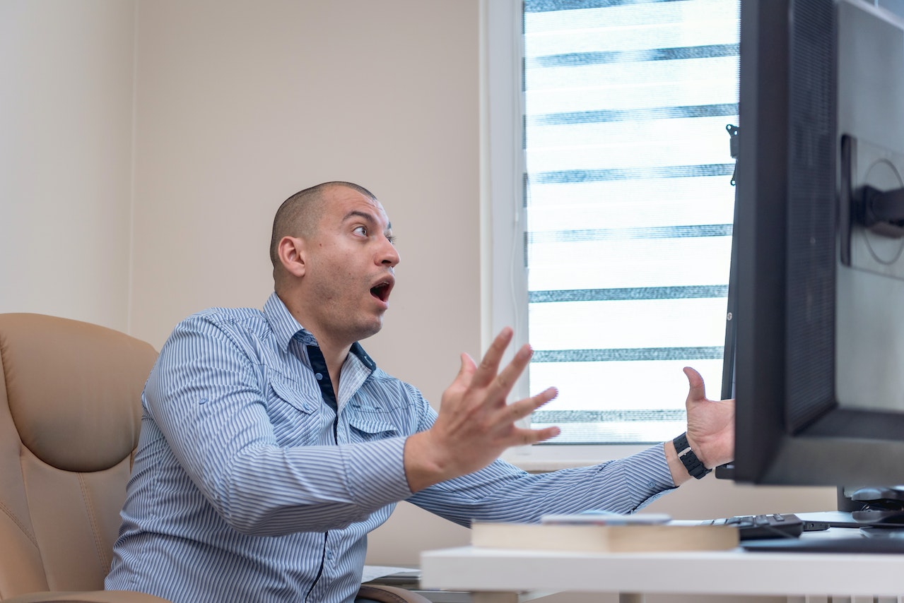Man is looking shocked and screaming ,watching on PC monitor.