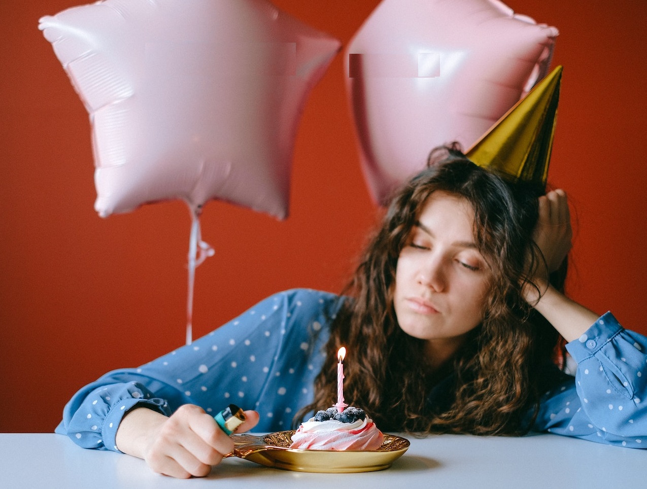 Woman is celebrating her birthday alone with small cake.
