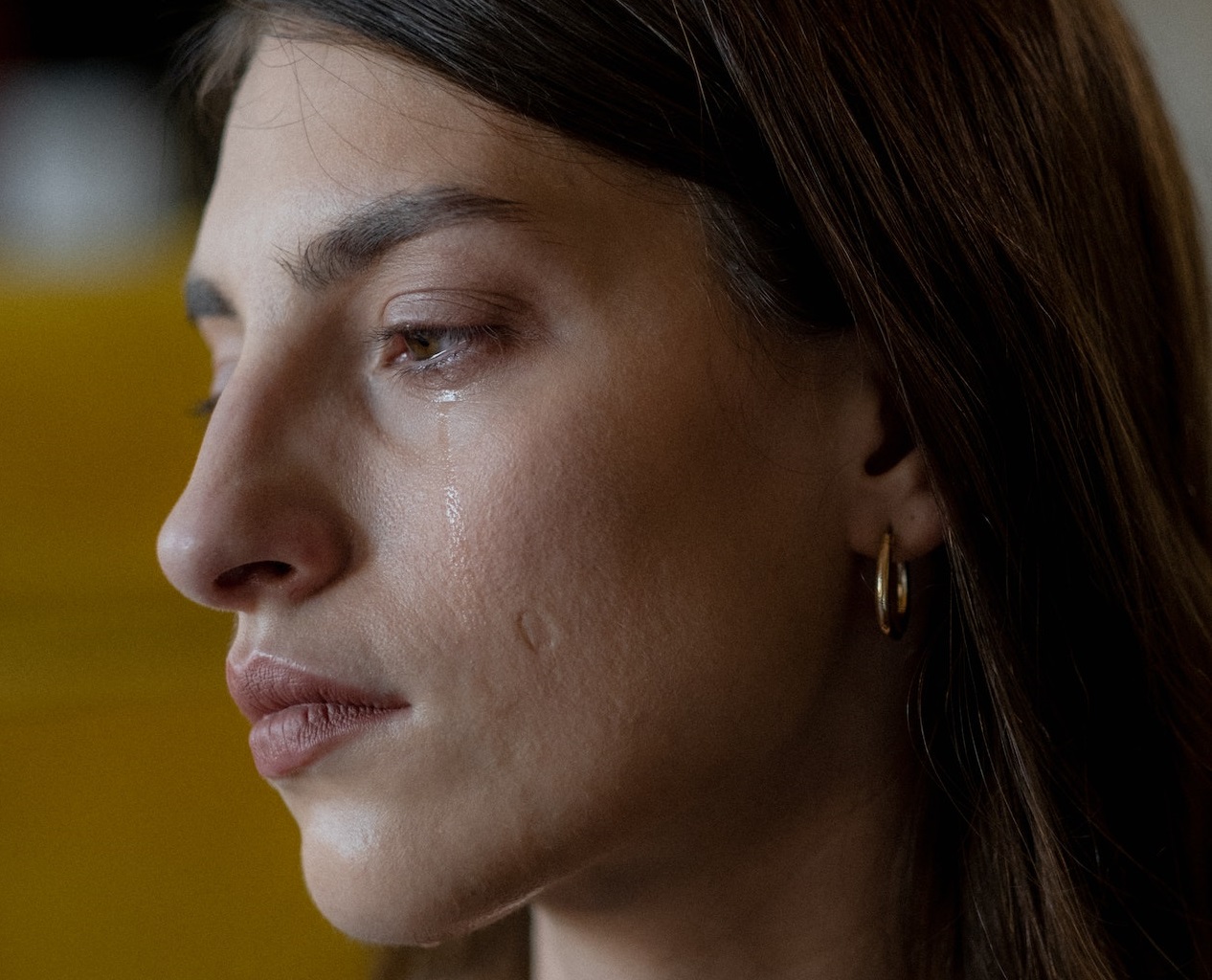 Close up photo of sad crying woman looking at side.