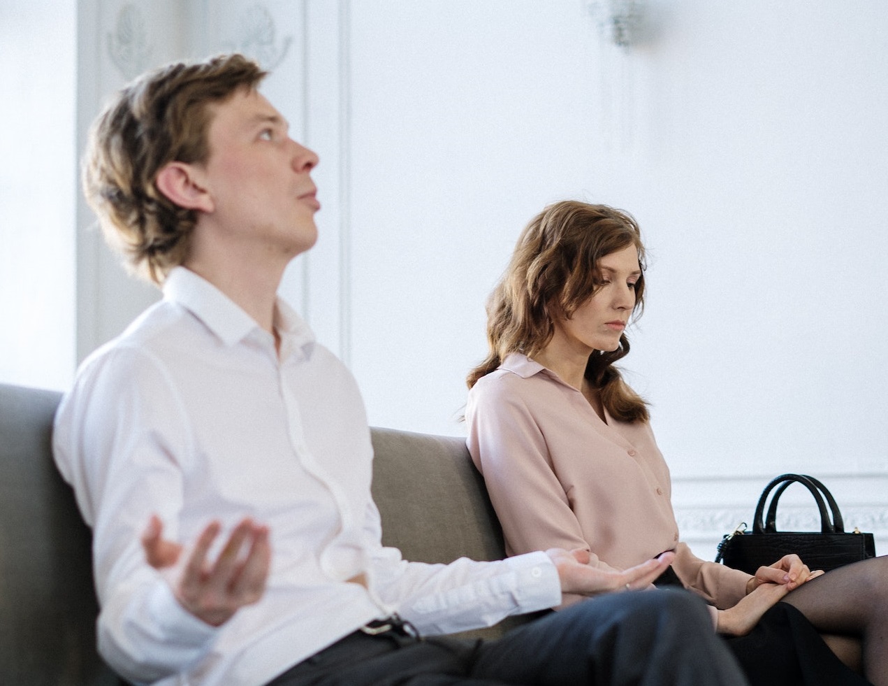 Man is talking with a woman seating on the bed.