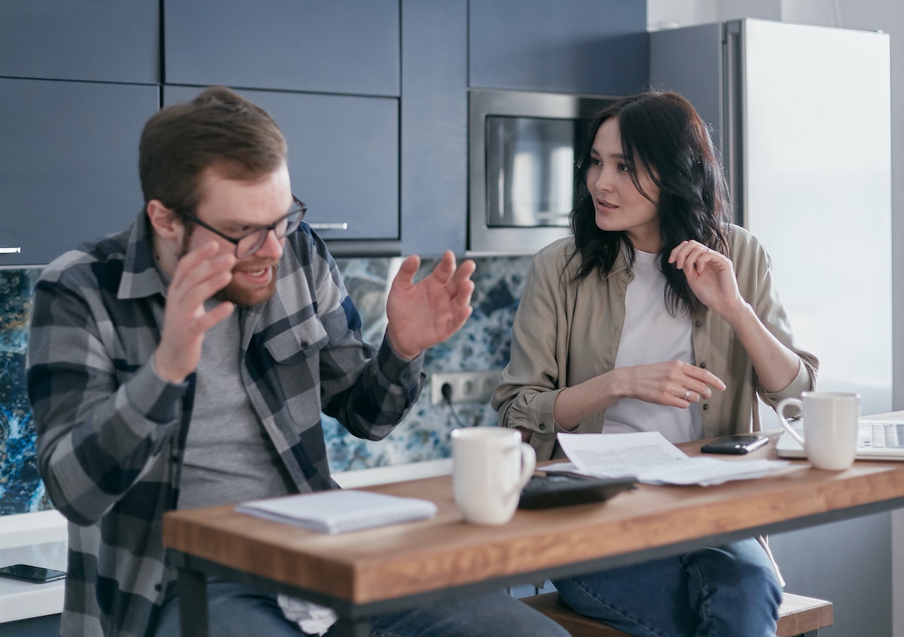 Couple arguing with documents in the kitchen.