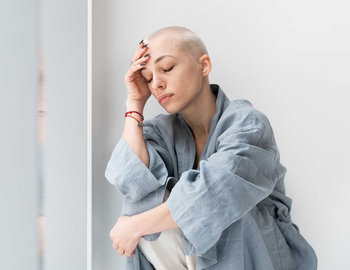 Woman with hospital clothes is seating on the floor.