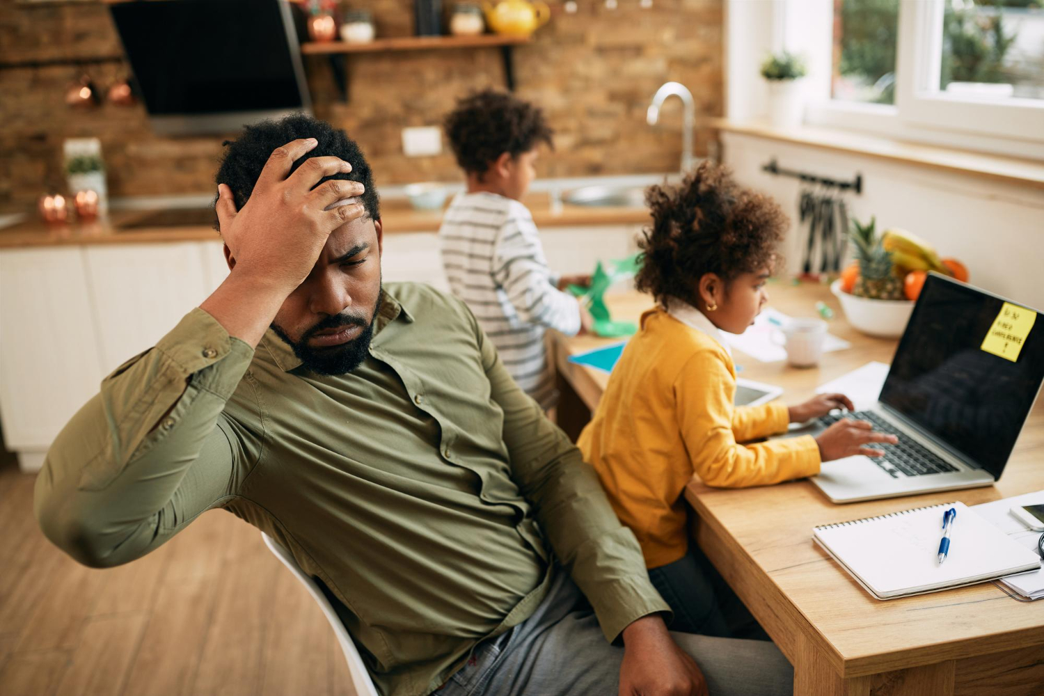 Black man is looking surprised seating at living room with his kids.