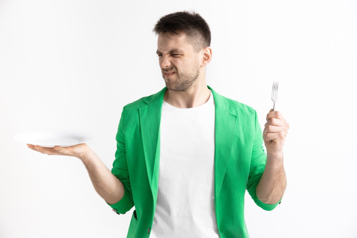 Man is holding a fork and a plate with angry face.
