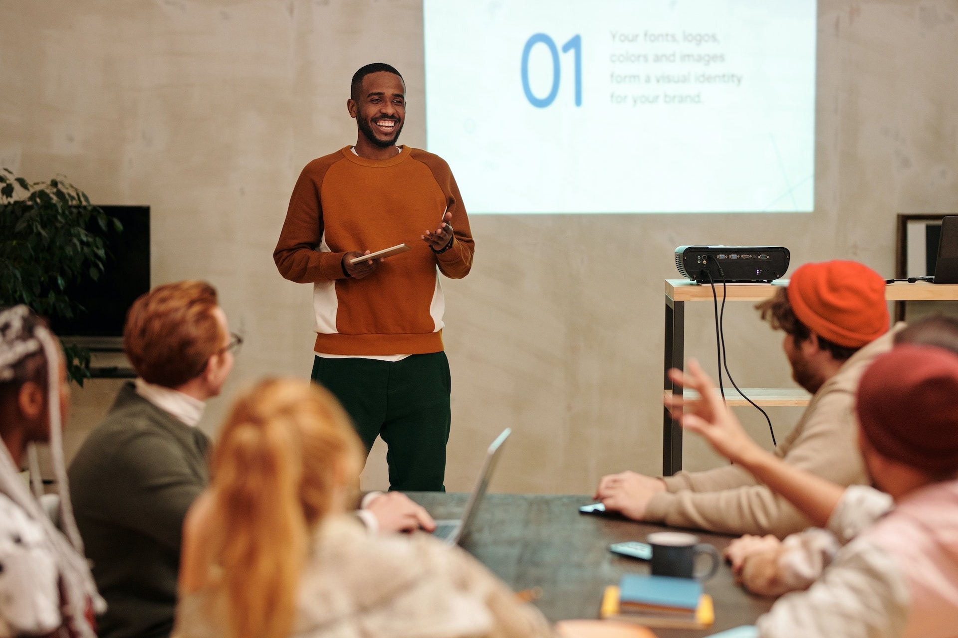 Man in brown sweater making a presentation