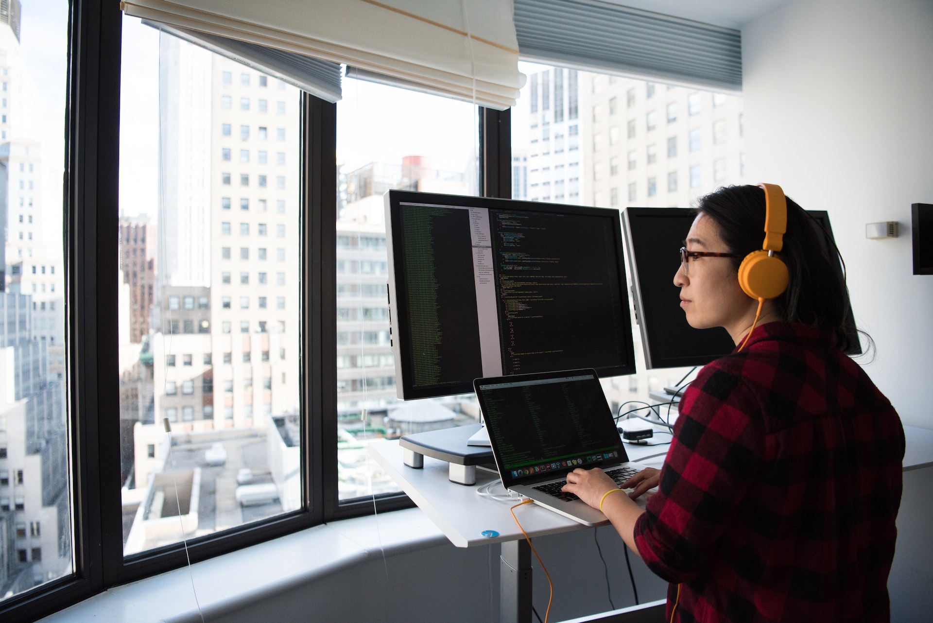 Woman in plaid shirt wearing headphones doing coding
