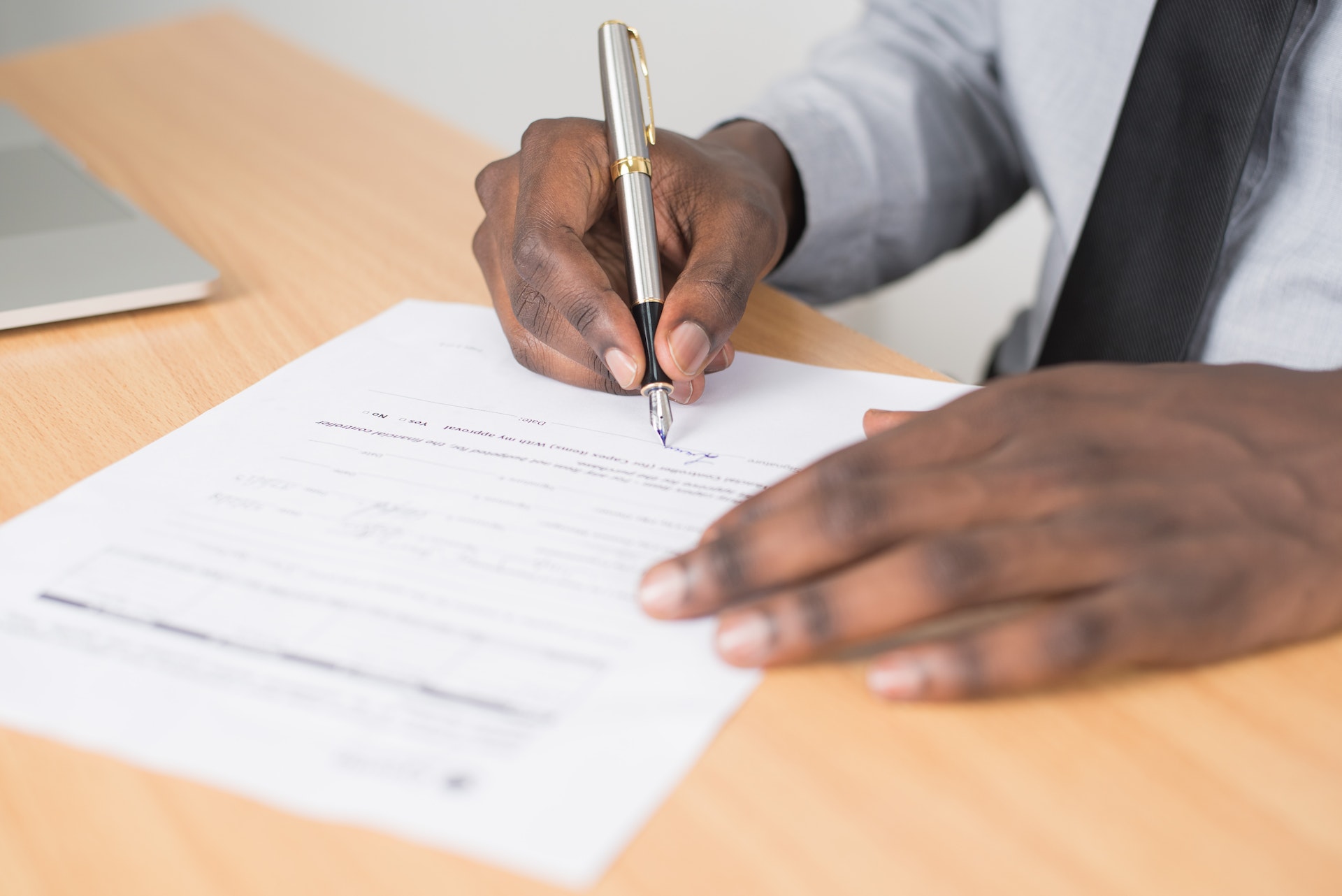 Man signing a paper with blue pen