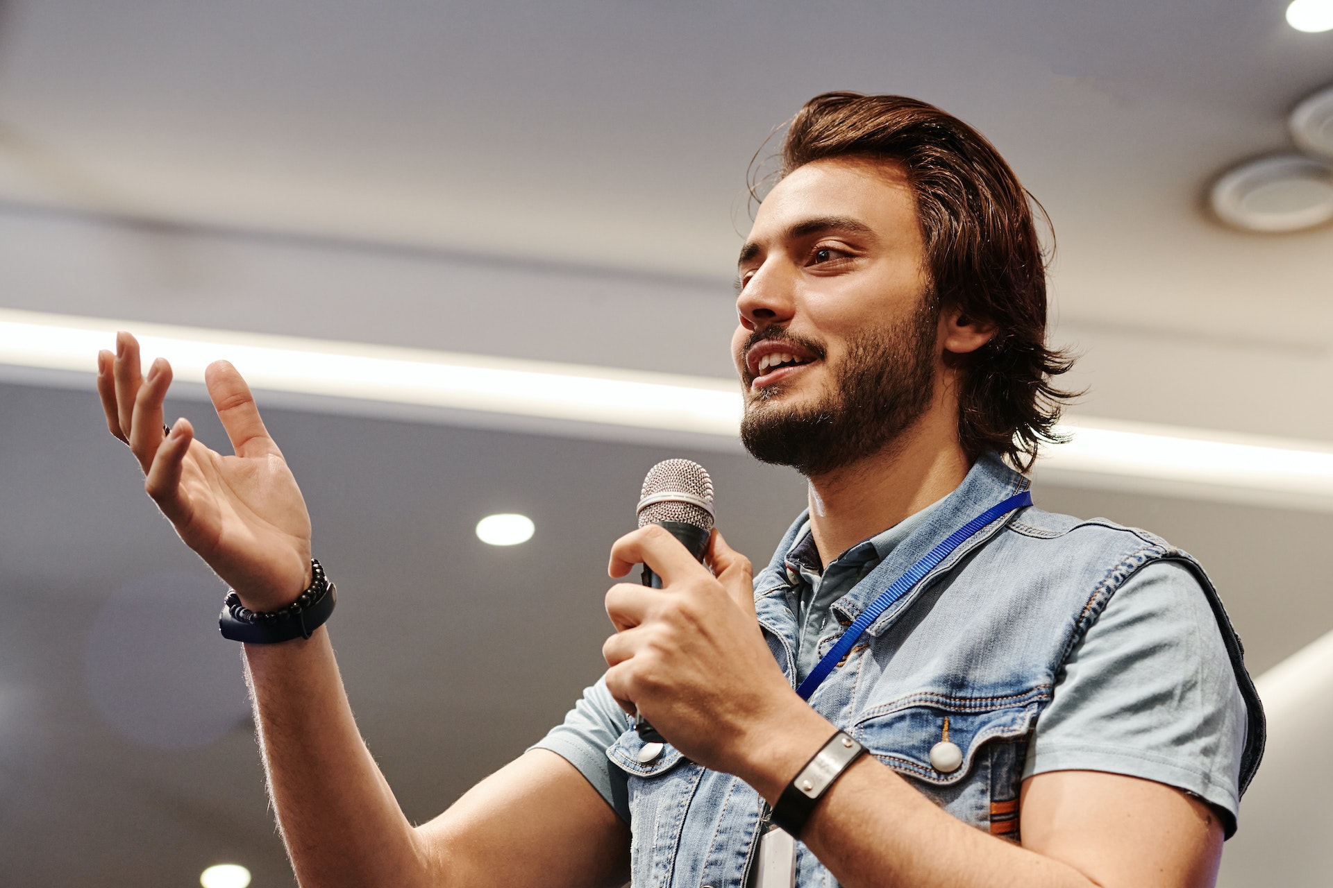 Man in denim vest holding a mic and speaking