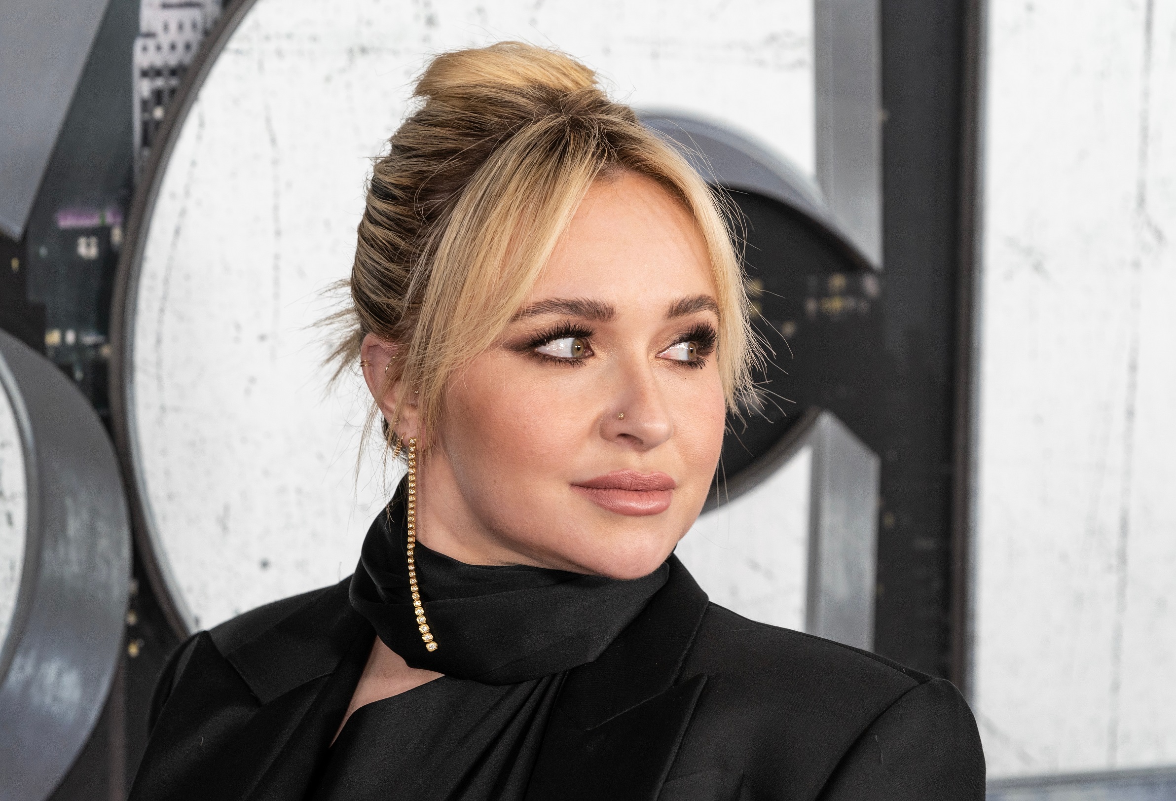 Hayden Panettiere wearing black dress and golden earrings looking at side - 2023