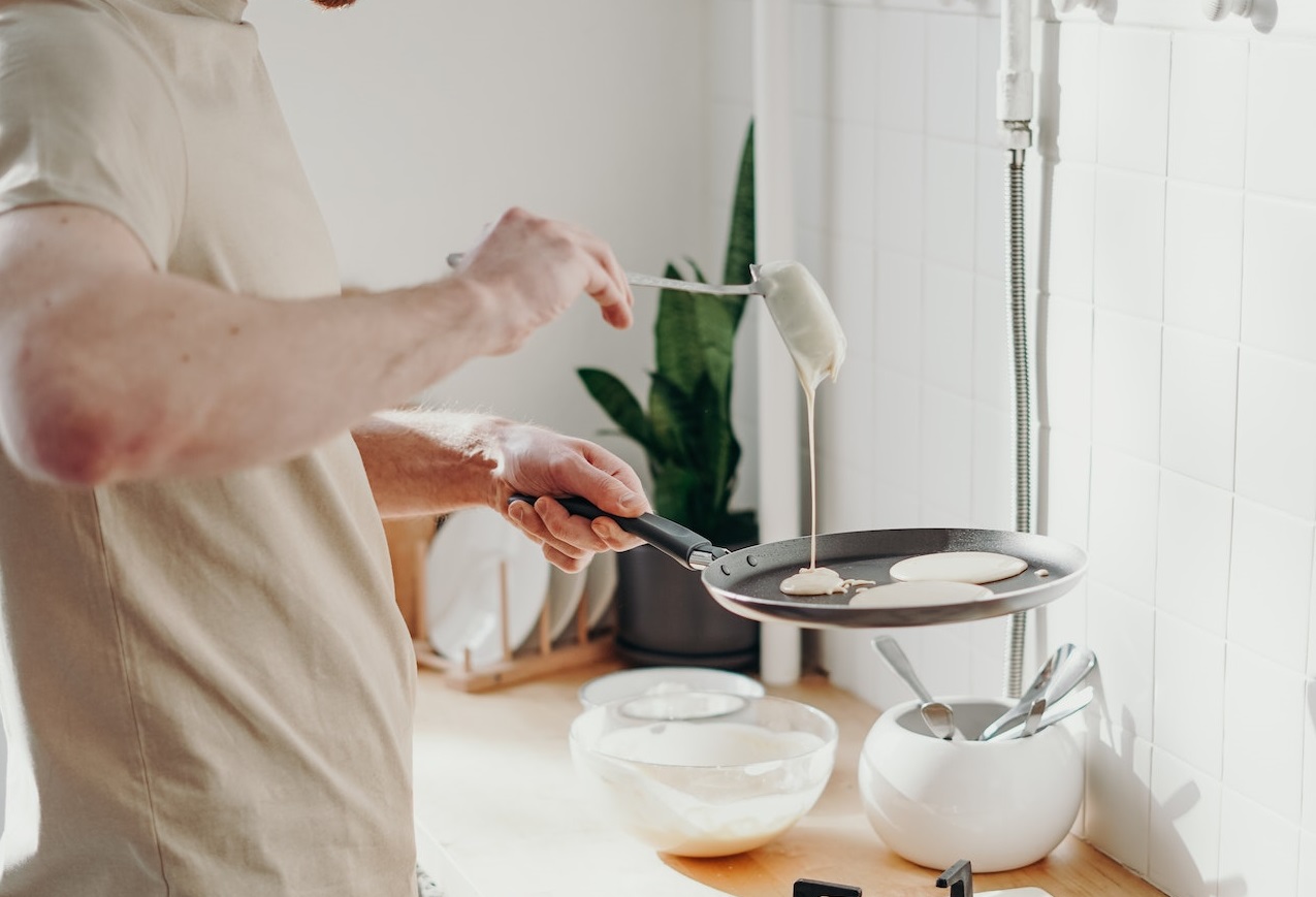 Man wearing grey shirt making a pancakes.