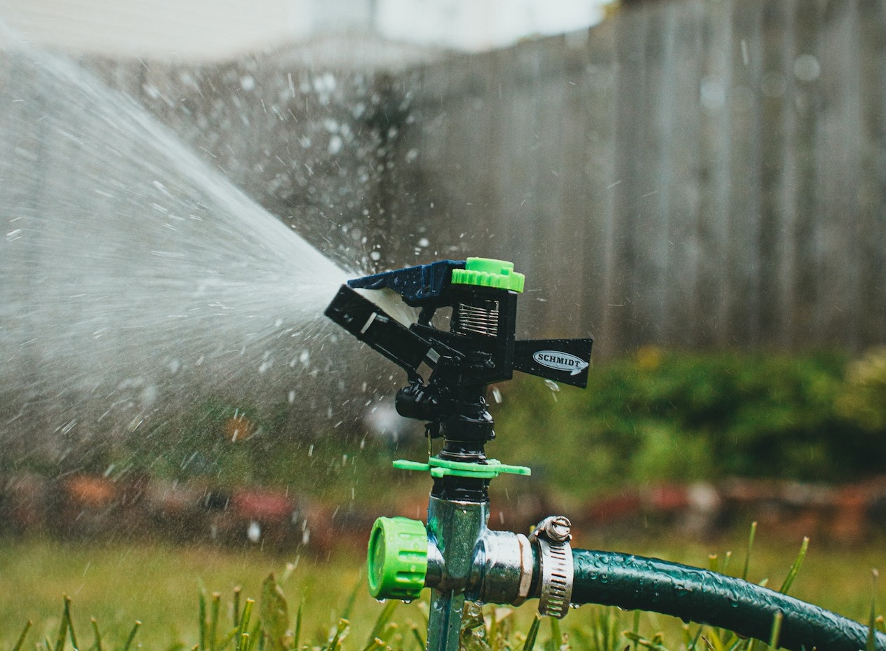 Sprinkler sending water on the green grass outside.