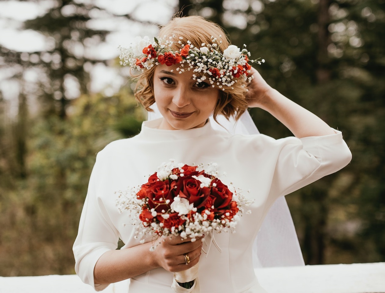 Bride in white dress and holding red bouquet.