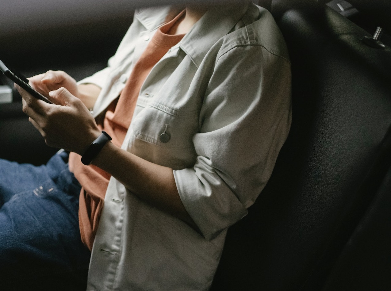 Man seating in the car and texting on the phone.