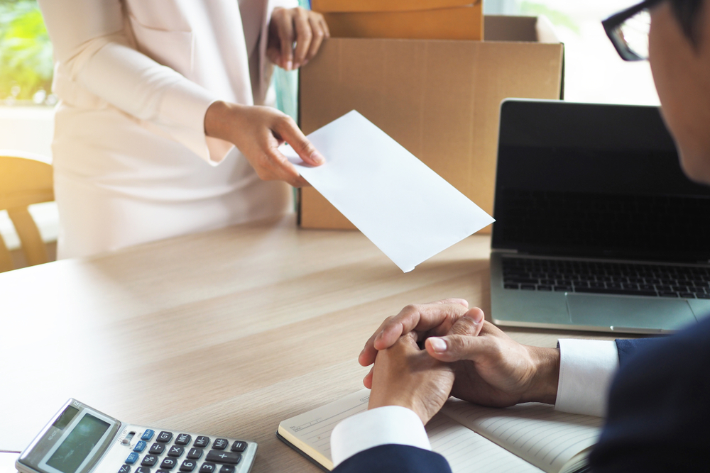 Woman in white suit giving letter of resignation to her boss