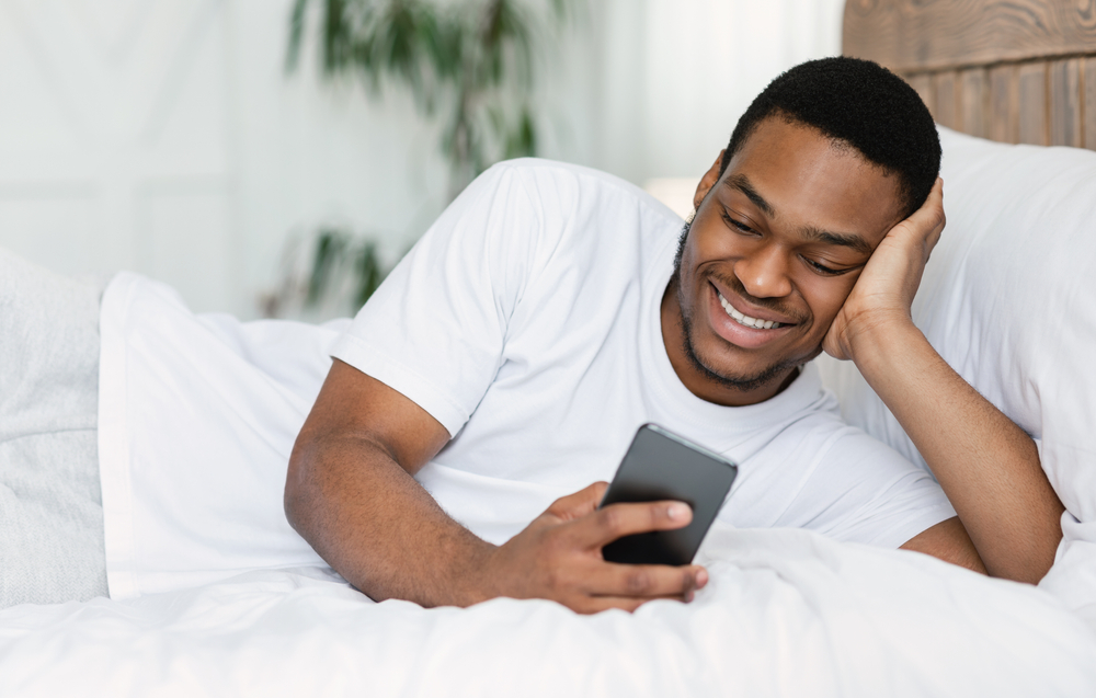 Man looking at phone lying in bed