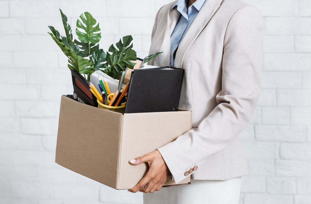 Woman holding a box of belongings leaving an office