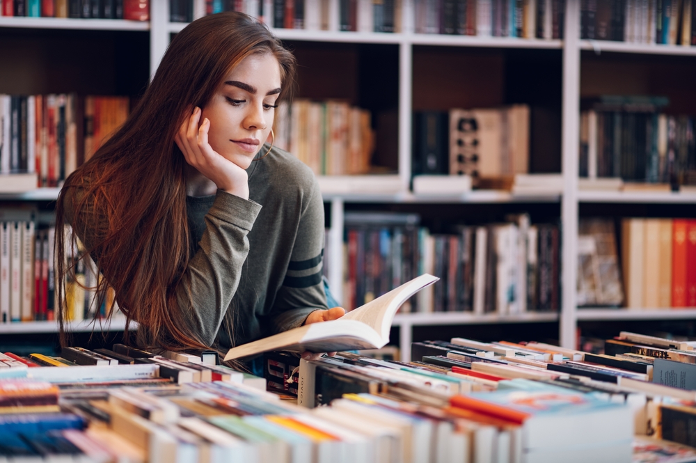 Young female customer reading a book in bookstore