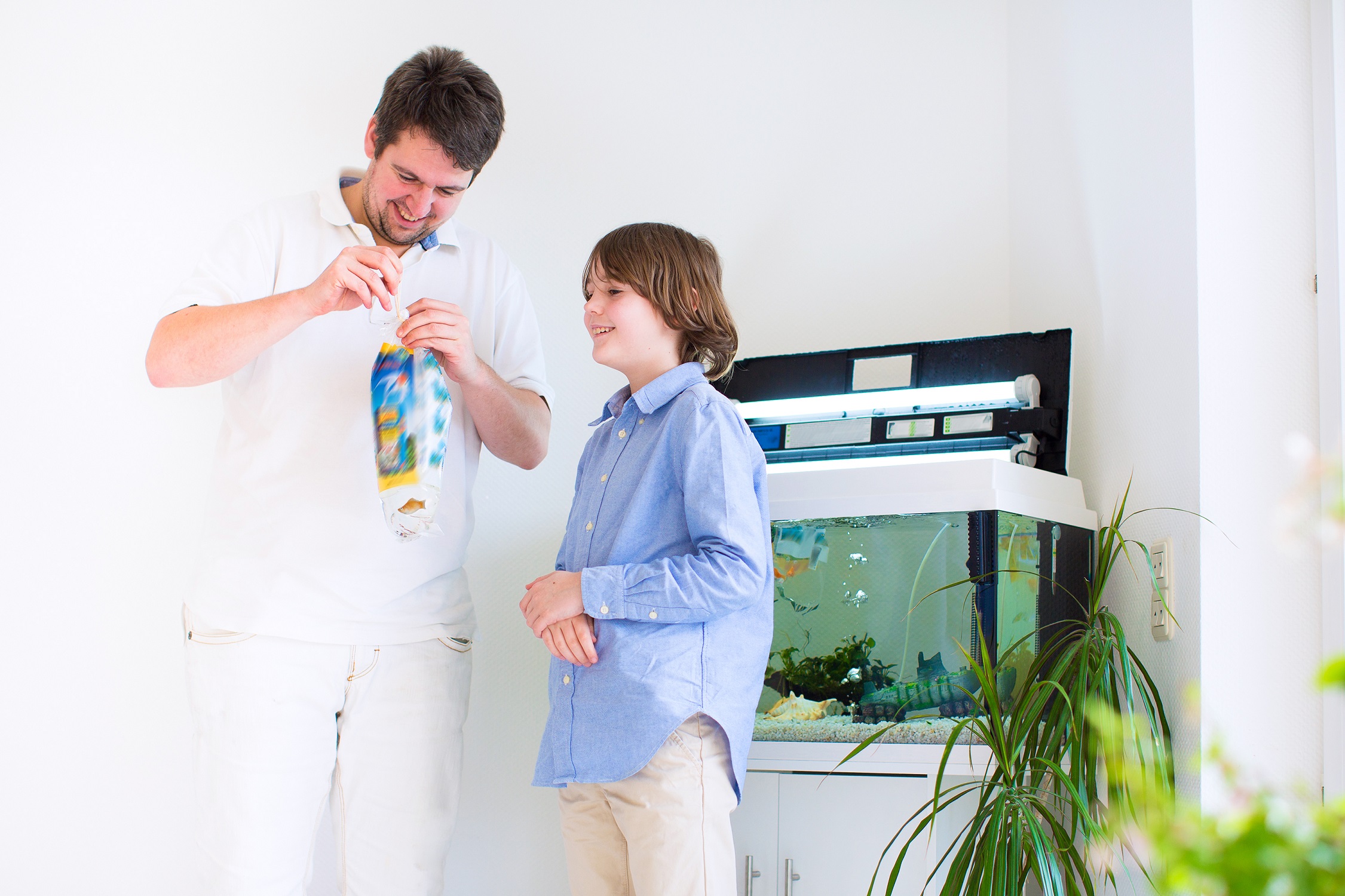 Father with his son standing by the fish tank.