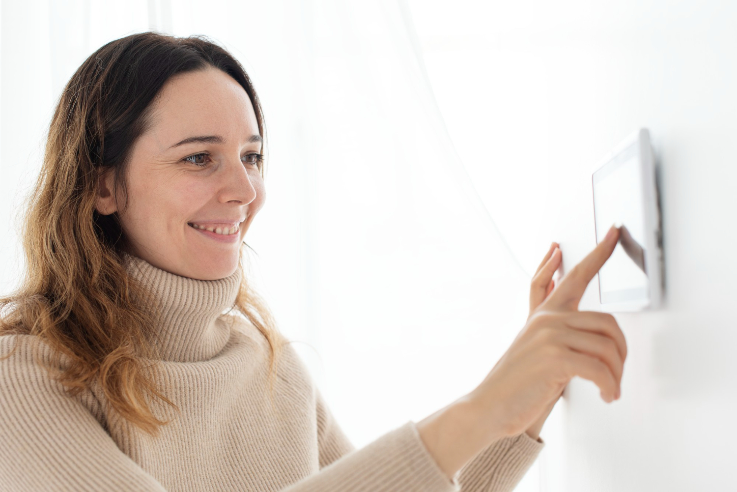 Woman setting the thermostat on the wall.