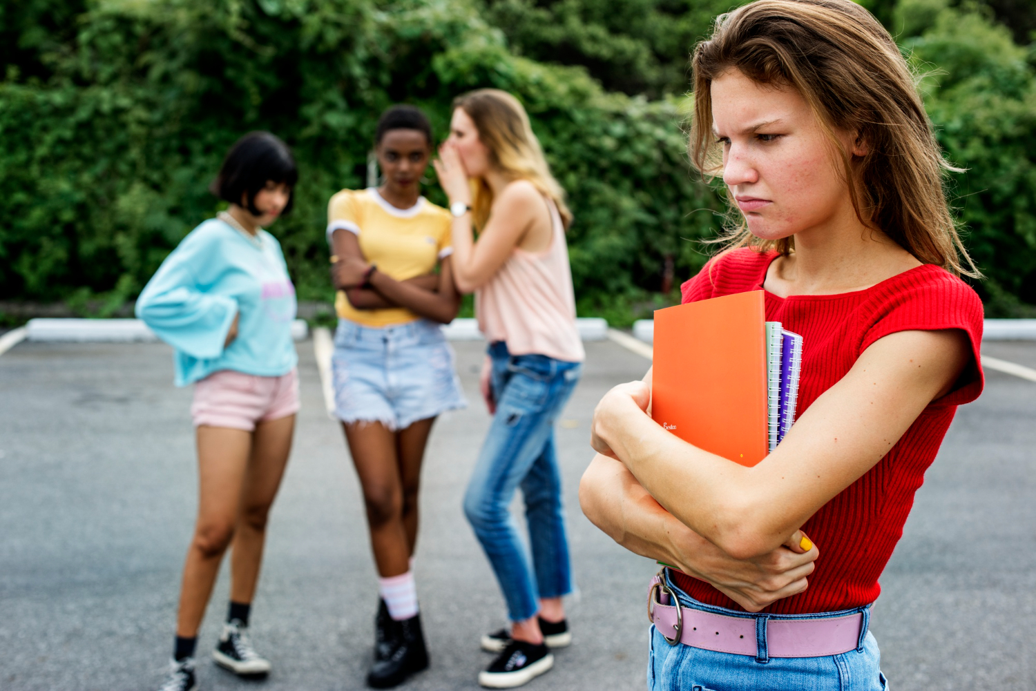 Sad girl wearing red shirt and holding a book in her hands walking.
