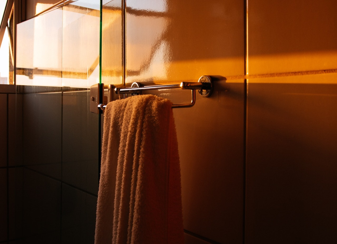 Towels hanging on a towel bar in the dark bathroom.