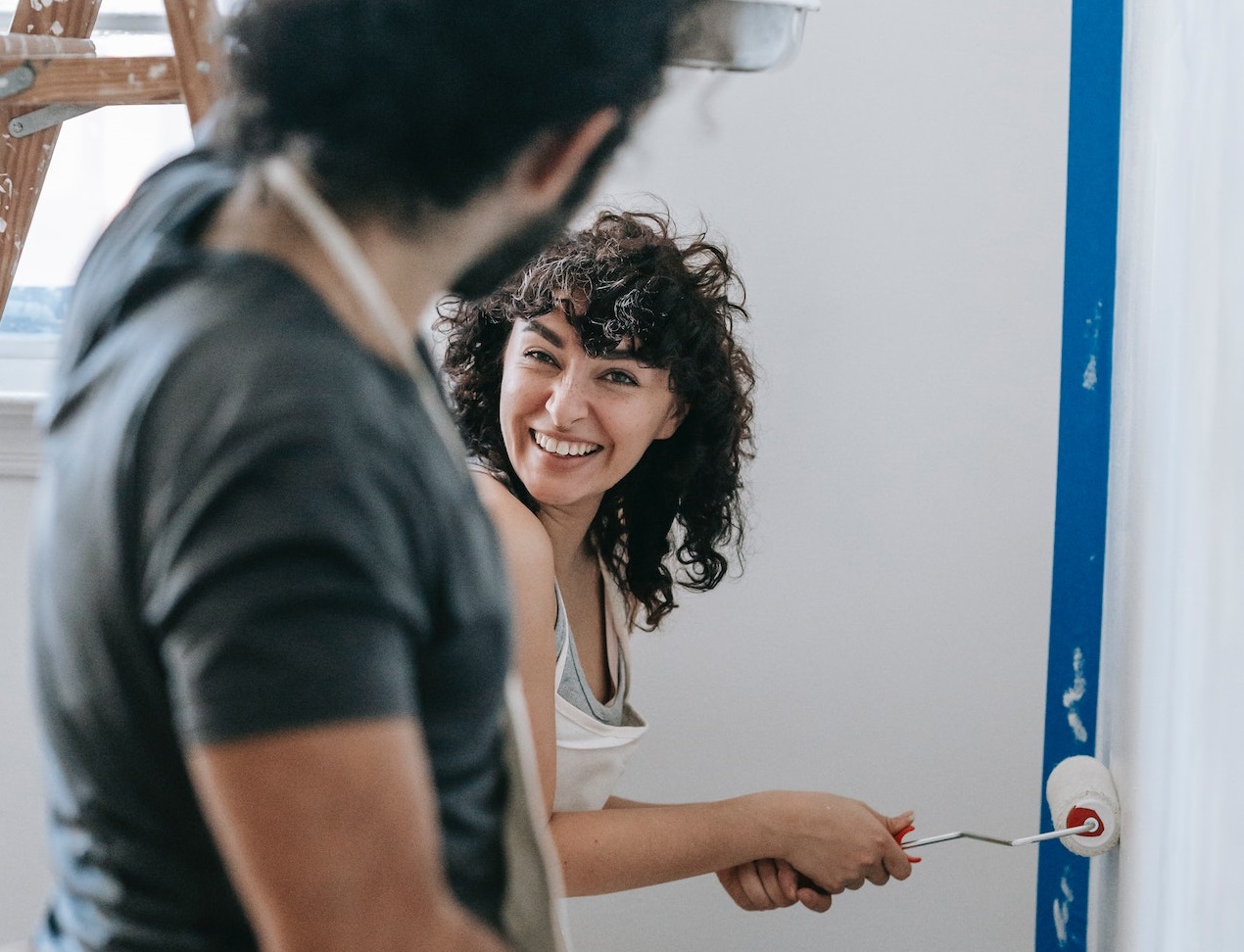 A couple enjoying while painting the walls.