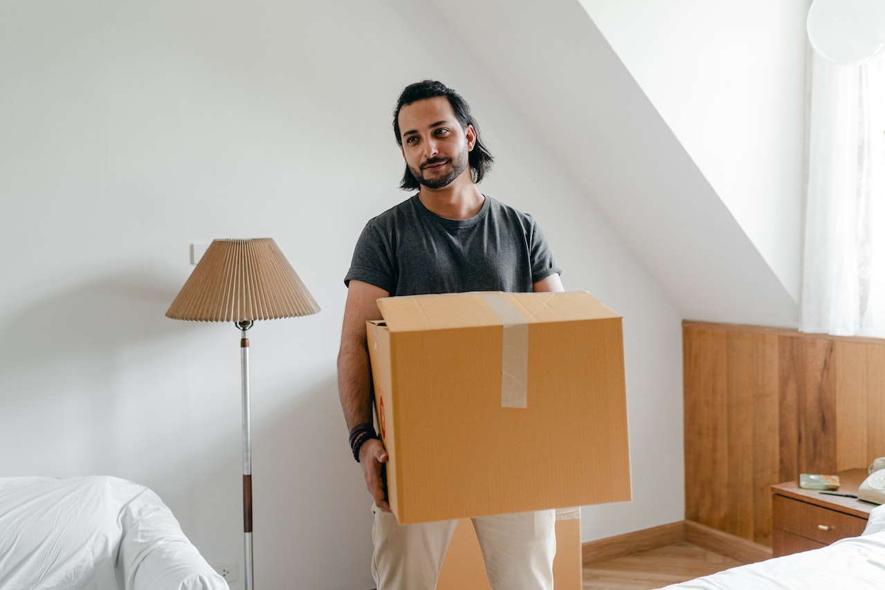 Man is holding a moving box in his hands.