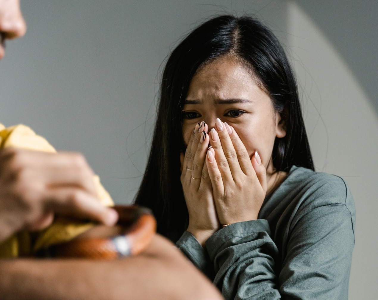 Scared woman looking at man holding a small snake in the hands.