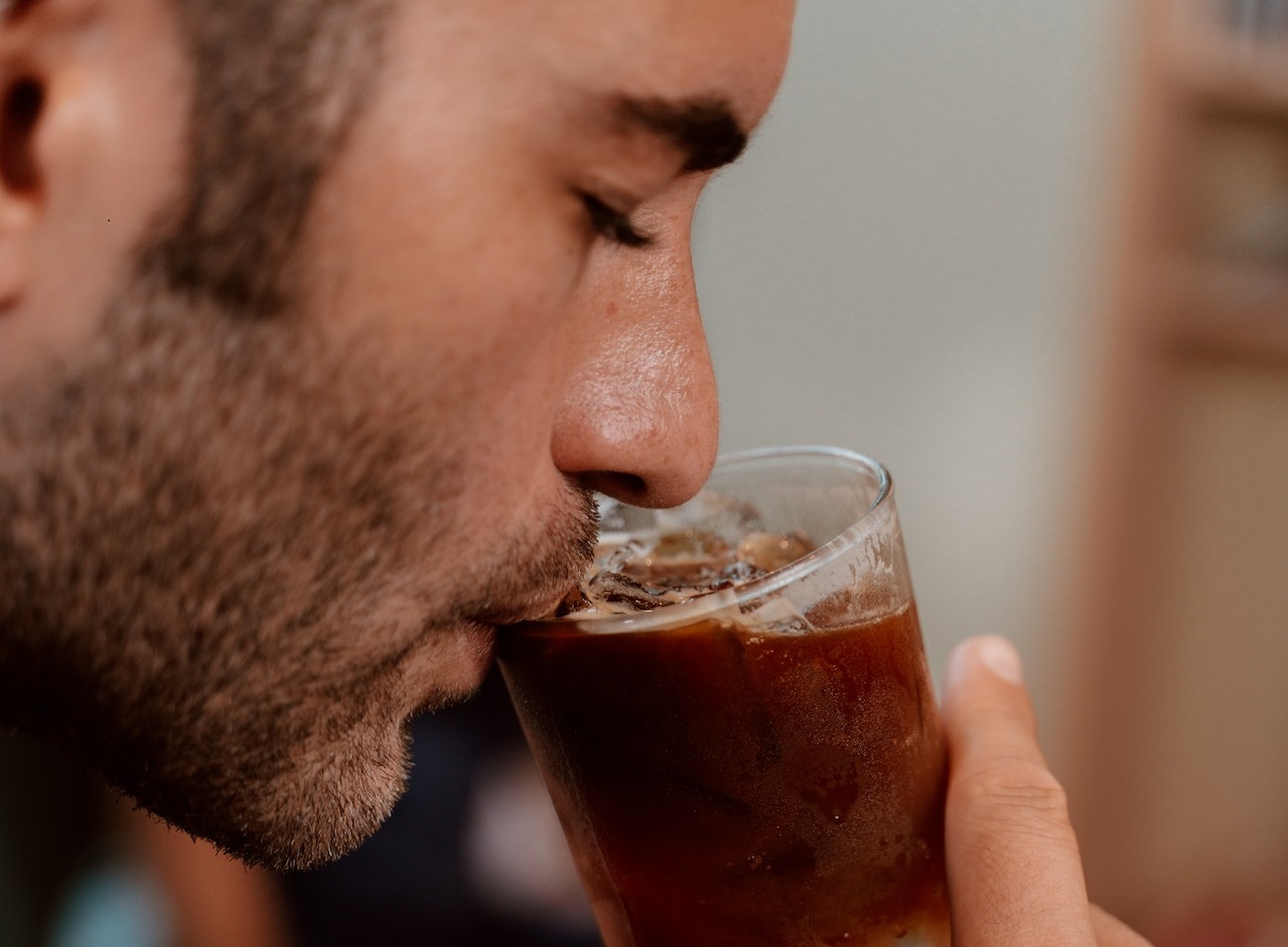 Close up photo of man drinking from glass.