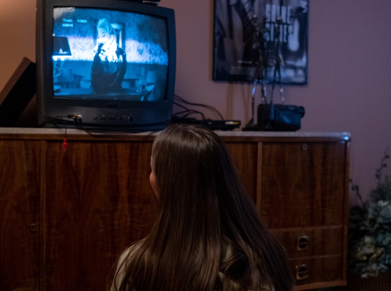 Woman seating on the floor and watching a tv.