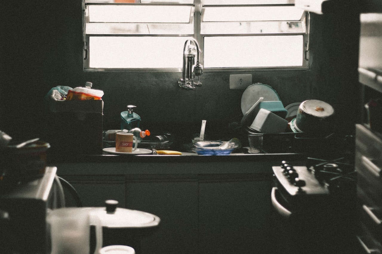 B&W photo of dark messy kitchen.