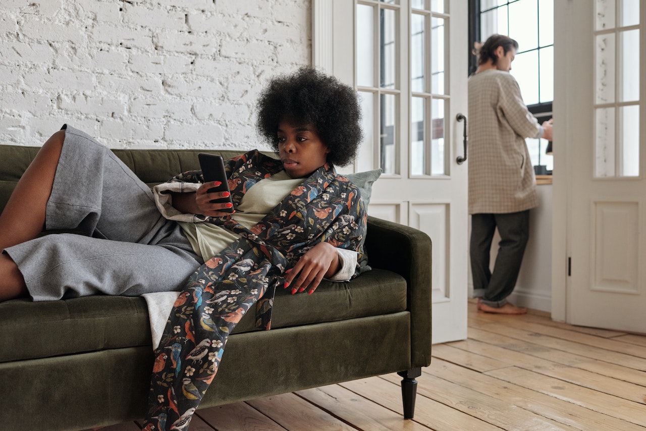 Woman lying on a sofa with a smartphone in hand.